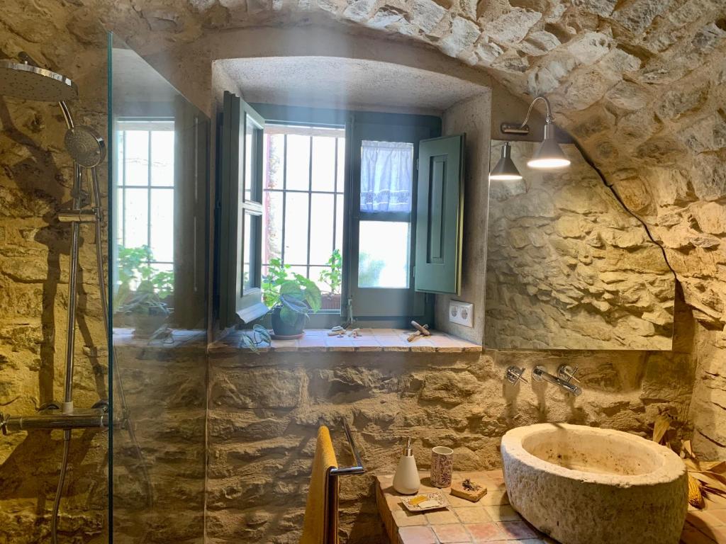 a stone bathroom with a sink and a window at Habitaciones rurales en Colomers in Colomés