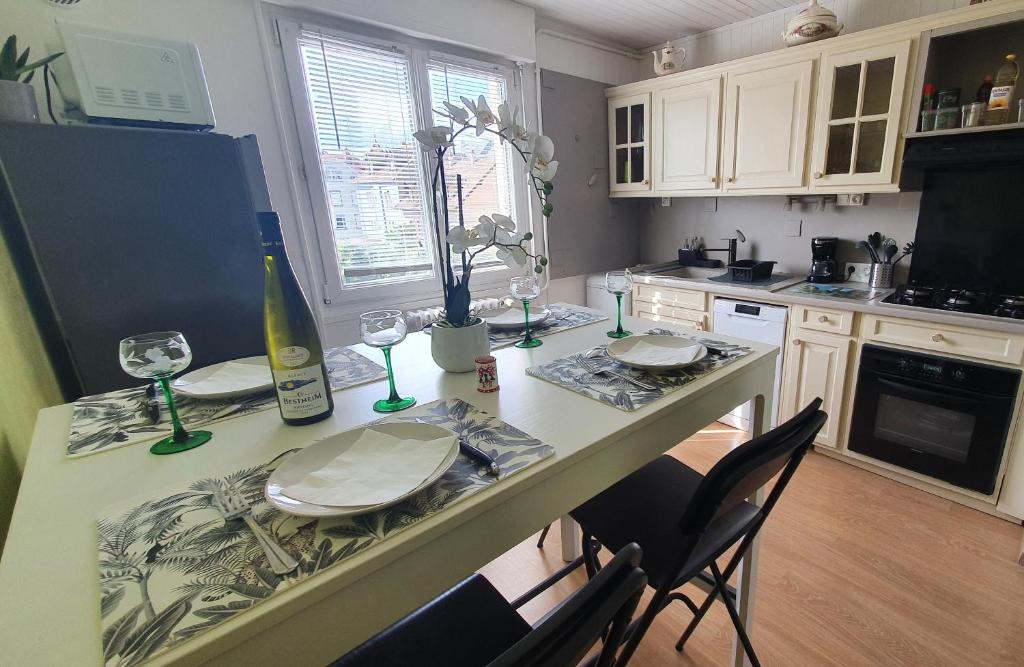 uma cozinha com uma mesa com pratos e copos de vinho em Le Bienvenue à Colmar, parking gratuit & balcon em Colmar