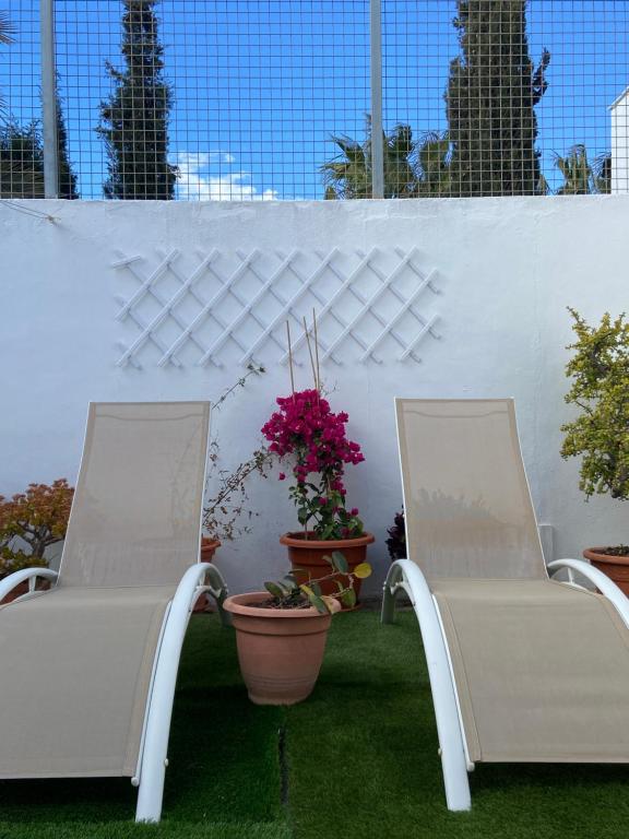 dwa białe krzesła siedzące na patio z roślinami w obiekcie Casa Rural El Jazminero w mieście Fernán Pérez