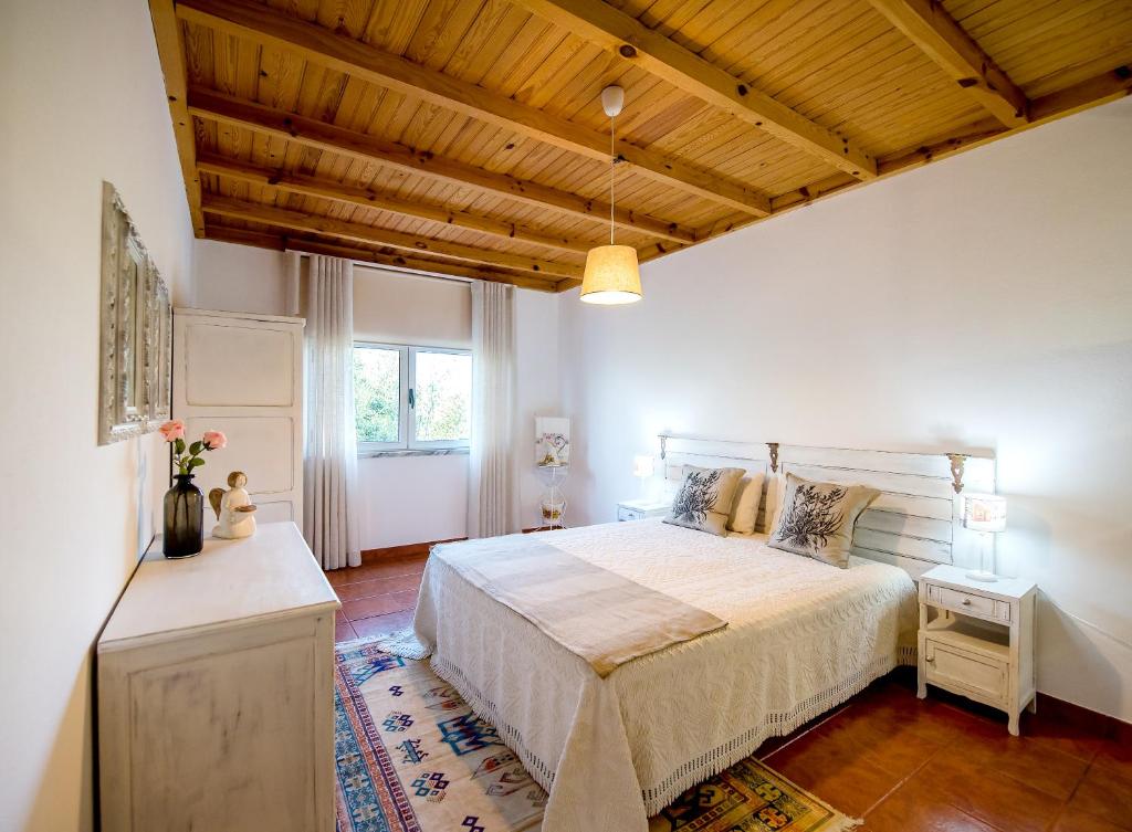 a bedroom with a large bed and a wooden ceiling at Vale do Grou Natura in Óbidos