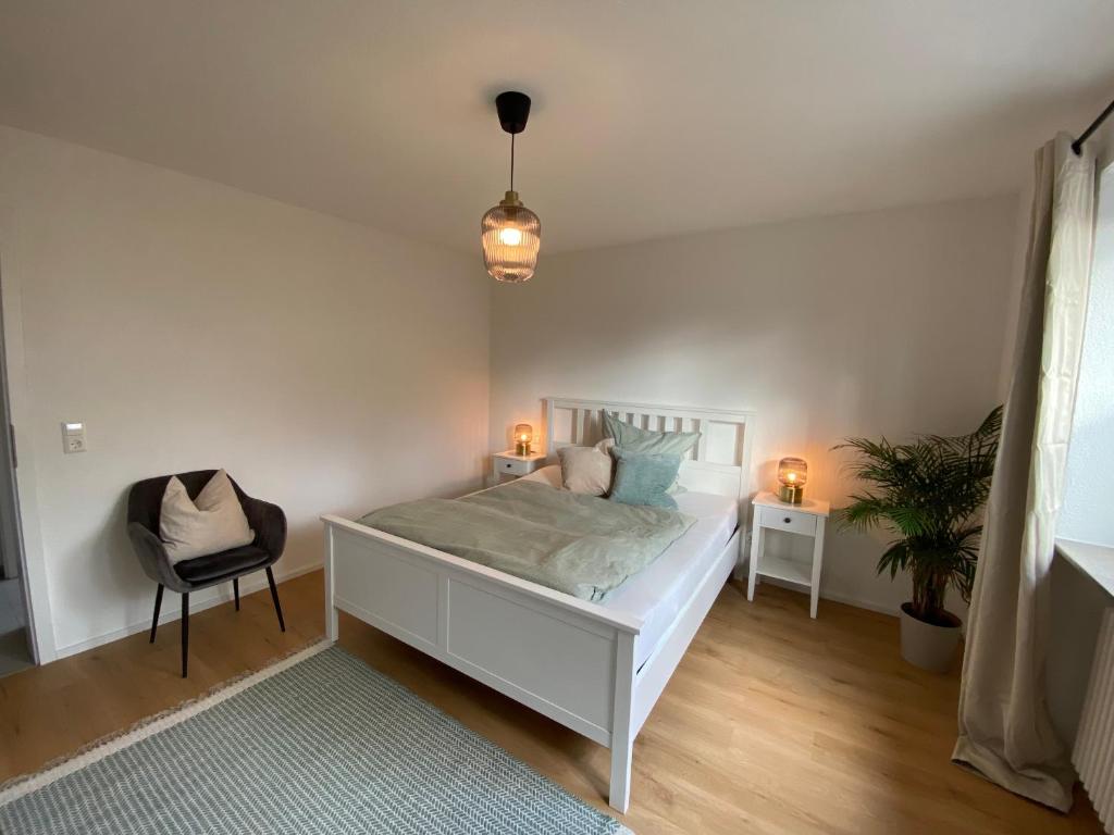 a bedroom with a white bed and a chair at Gemütliche Wohnung am Federsee in Bad Buchau