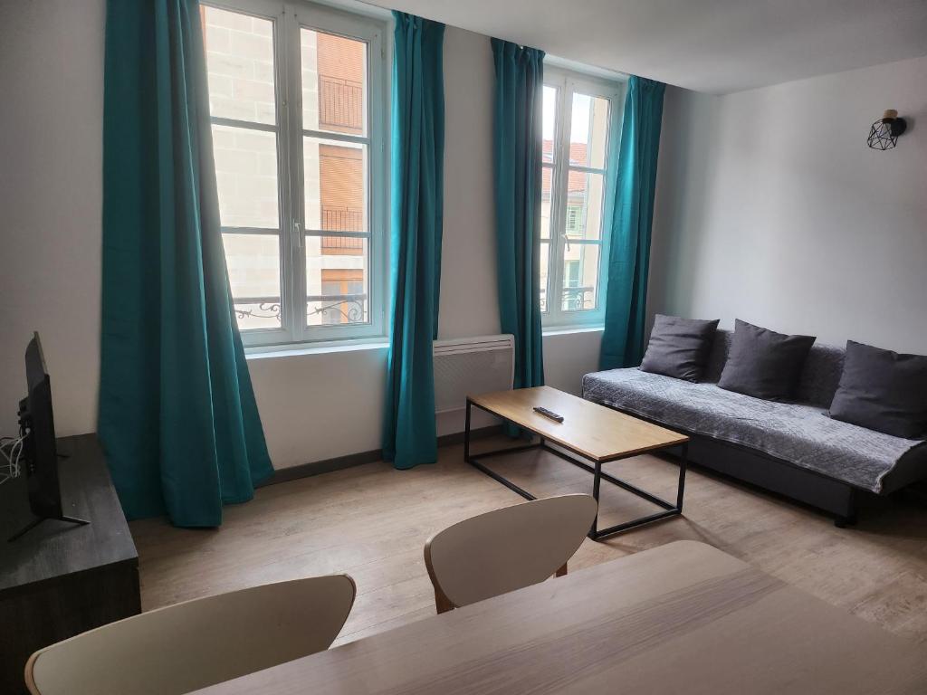 een woonkamer met een bank en een tafel bij Spacieux 2 chambres, paisible in Bar-le-Duc