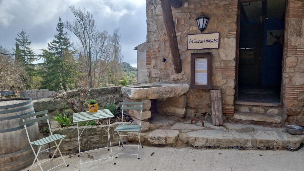 Cal Tous, La Socarrimada في Rojals: زوج من الكراسي وطاولة خارج المبنى