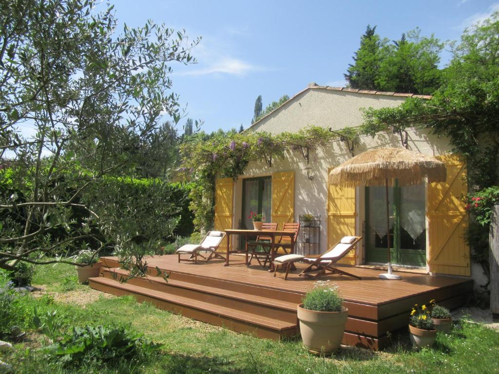 una terraza de madera con mesa y sillas en un patio en KiOui en Rennes-les-Bains