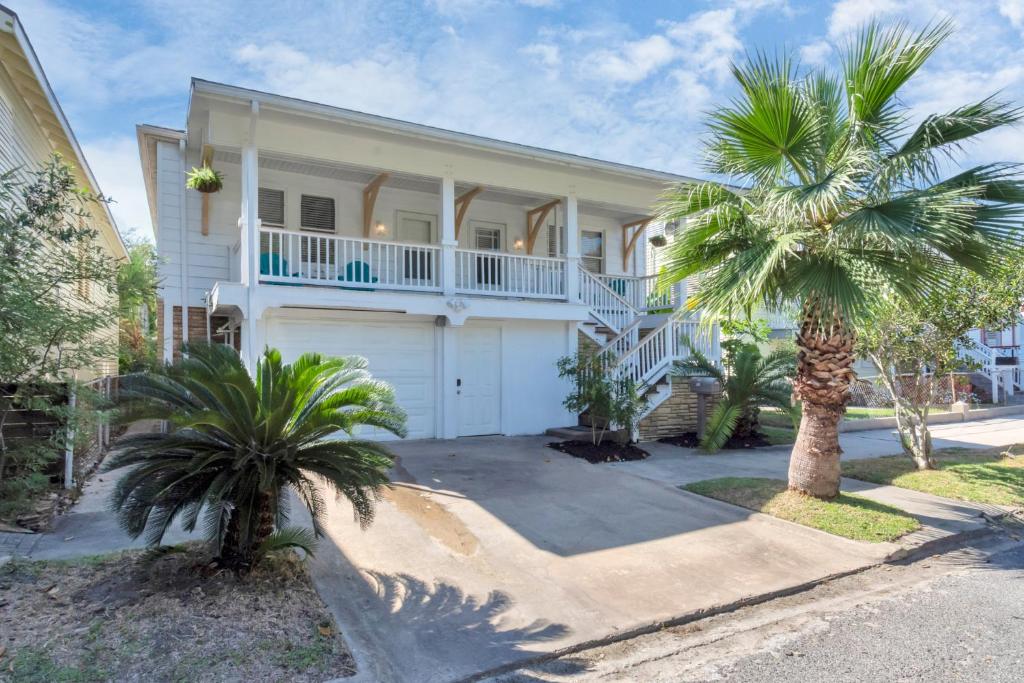 a white house with palm trees in front of it at Cozy Historic Galveston House-8 min walk to beach! in Galveston