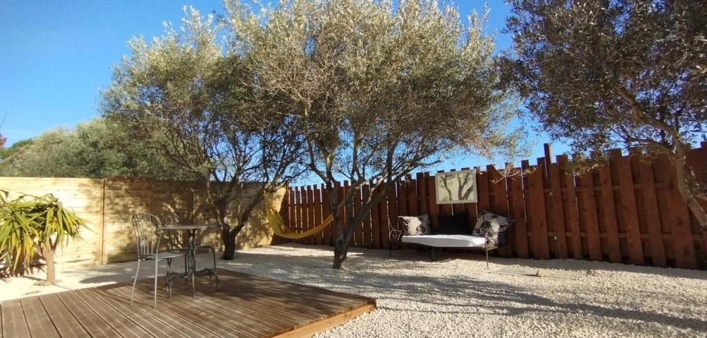 un patio trasero con una valla, una silla y una mesa en Au Cabanon, en Saint-Laurent-dʼAigouze