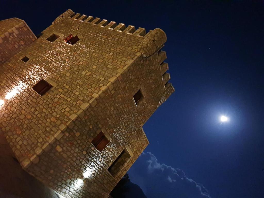 une tour d'horloge avec la lune en arrière-plan dans l'établissement Mani Tower, à Kamáres
