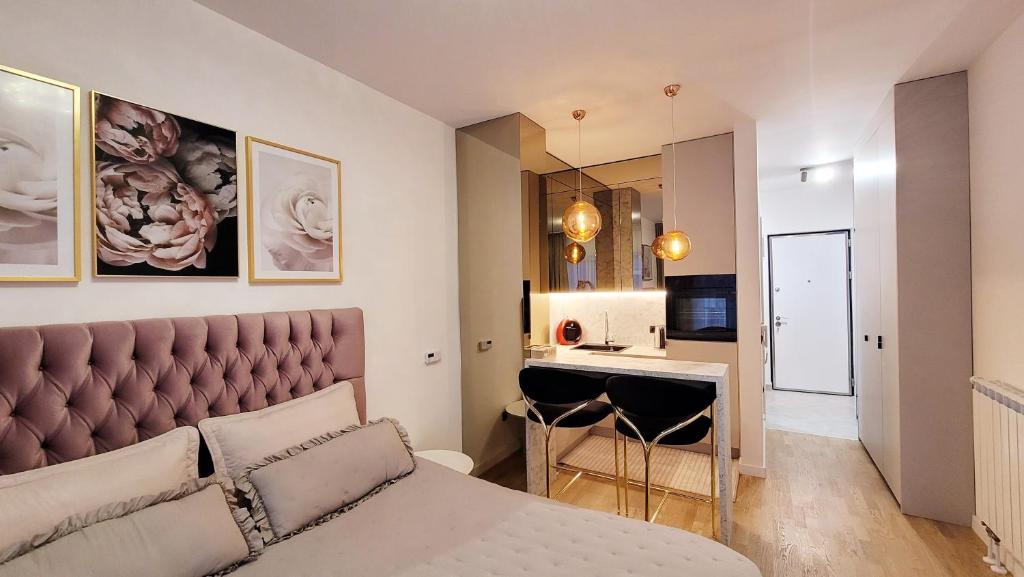 a bedroom with a king sized bed and a kitchen at Studio apartment Lora Lux - Bulevar in Sarajevo