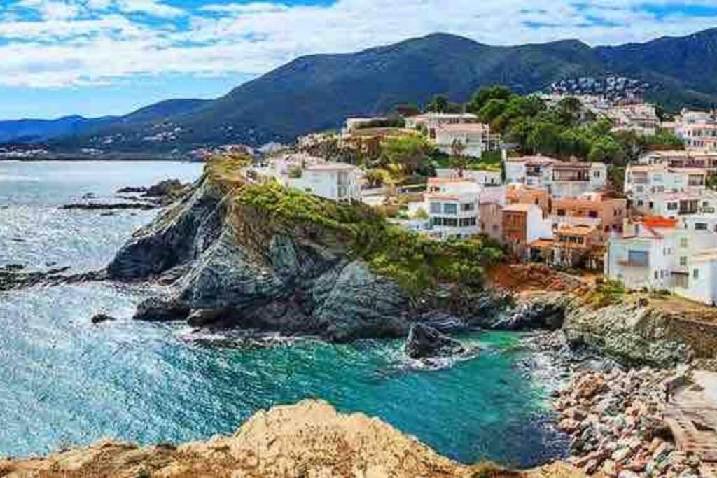 um grupo de casas numa costa rochosa com o oceano em Apartamento con Piscina en Llança em Llançà