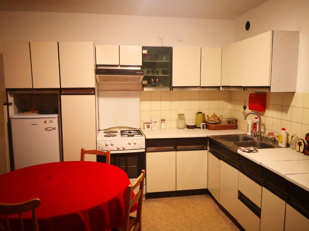 uma cozinha com armários brancos e uma mesa vermelha em Stanovanje v Žalcu em Žalec