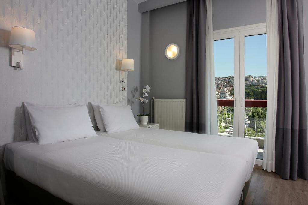 a white bed in a hotel room with a window at Abc Hotel in Thessaloniki