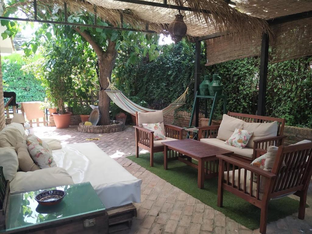 a patio with couches and a hammock and a tree at Dormir entre limones, Casa de invitados en vivienda familiar in Dos Hermanas