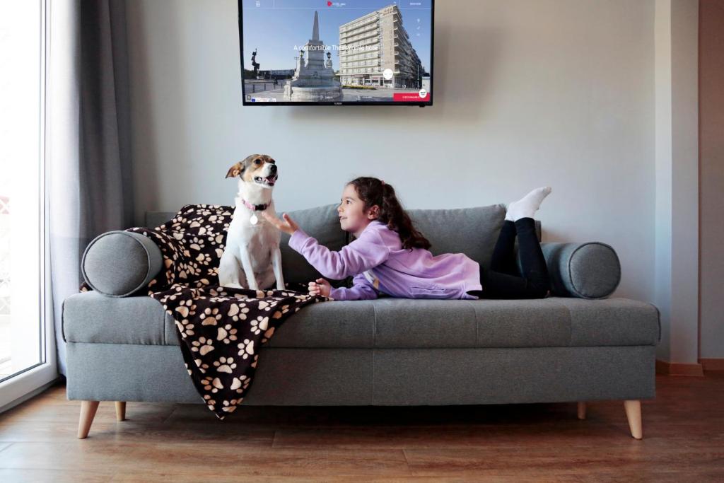 a little girl sitting on a couch with a dog at Abc Hotel in Thessaloniki