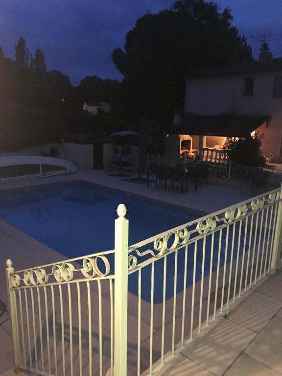 una valla blanca junto a una piscina por la noche en Studio privé, en Cazilhac