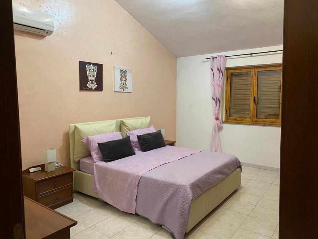 een slaapkamer met een bed met paarse lakens en een raam bij Villa Sophie in SantʼAgata di Militello