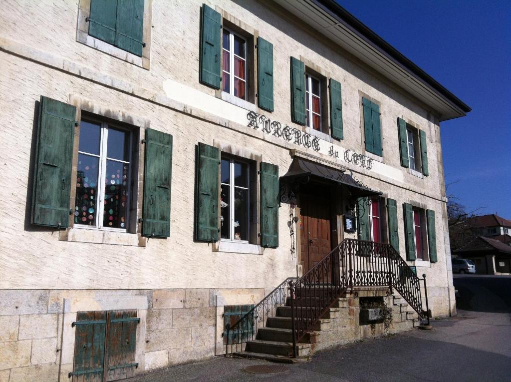 ein altes Gebäude mit grünen Fensterläden und einer Tür in der Unterkunft Chambres d'hôtes Chez Epicure in Ballaigues