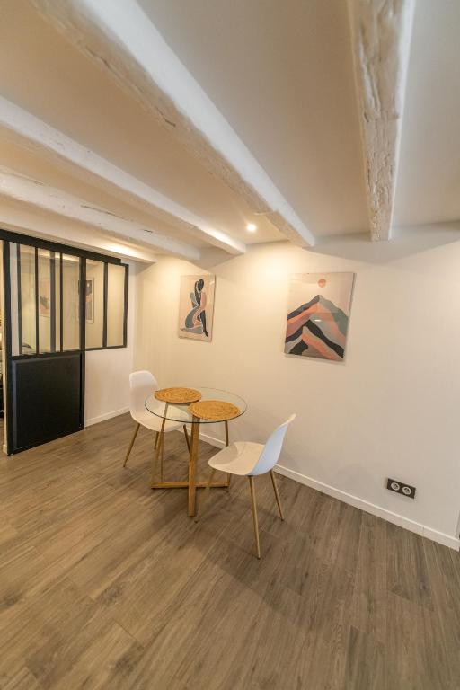 Cette chambre comprend une table, des chaises et des peintures murales. dans l'établissement CONFORTABLE 2 PIÈCES AU CŒUR DU CENTRE HISTORIQUE, à Vienne