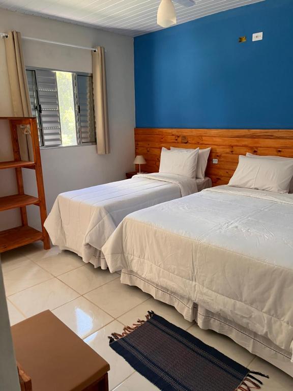 sypialnia z 2 łóżkami i niebieską ścianą w obiekcie Chalé Canto da Viola w mieście São Roque