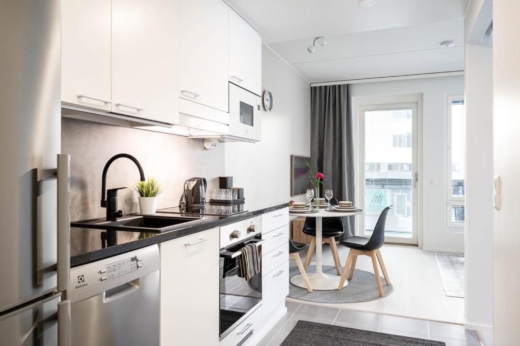 a kitchen with white cabinets and a table with a chair at Apartment near the train station, free parking &Netflix in Kuopio