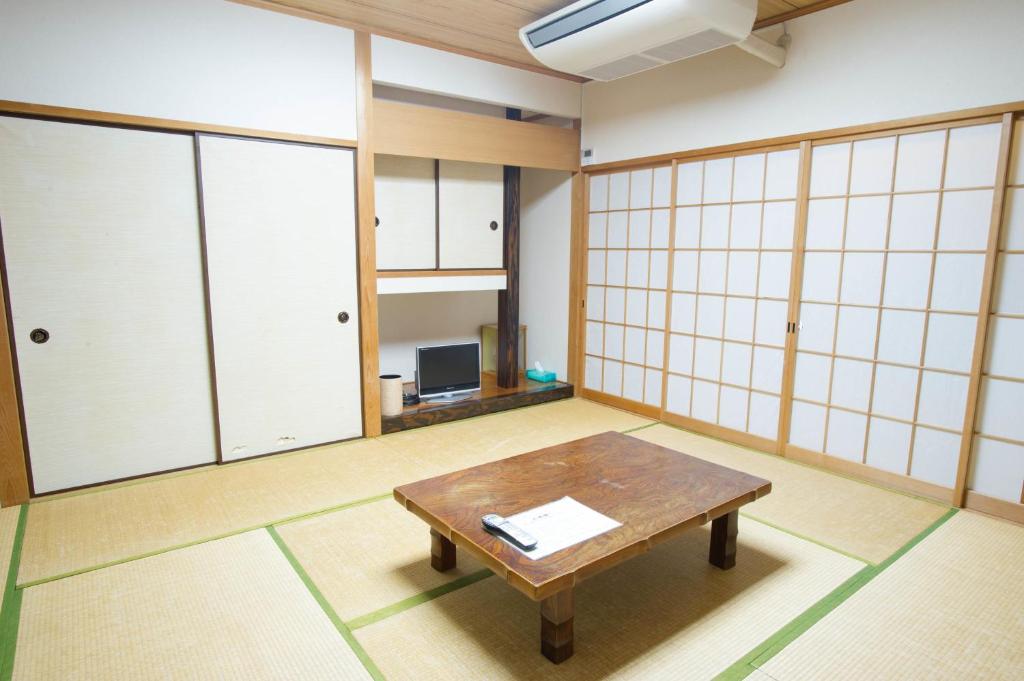 a room with a table in a room with glass walls at 駅前山小屋A-yard in Ome