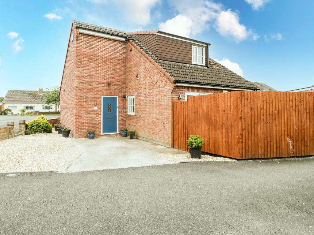 a brick house with a wooden fence at 8A Rosewood Avenue in Burnham on Sea