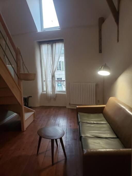 salon z kanapą, stołem i oknem w obiekcie Studio au centre de Guémené-sur-Scorff w mieście Guéméné-sur-Scorff