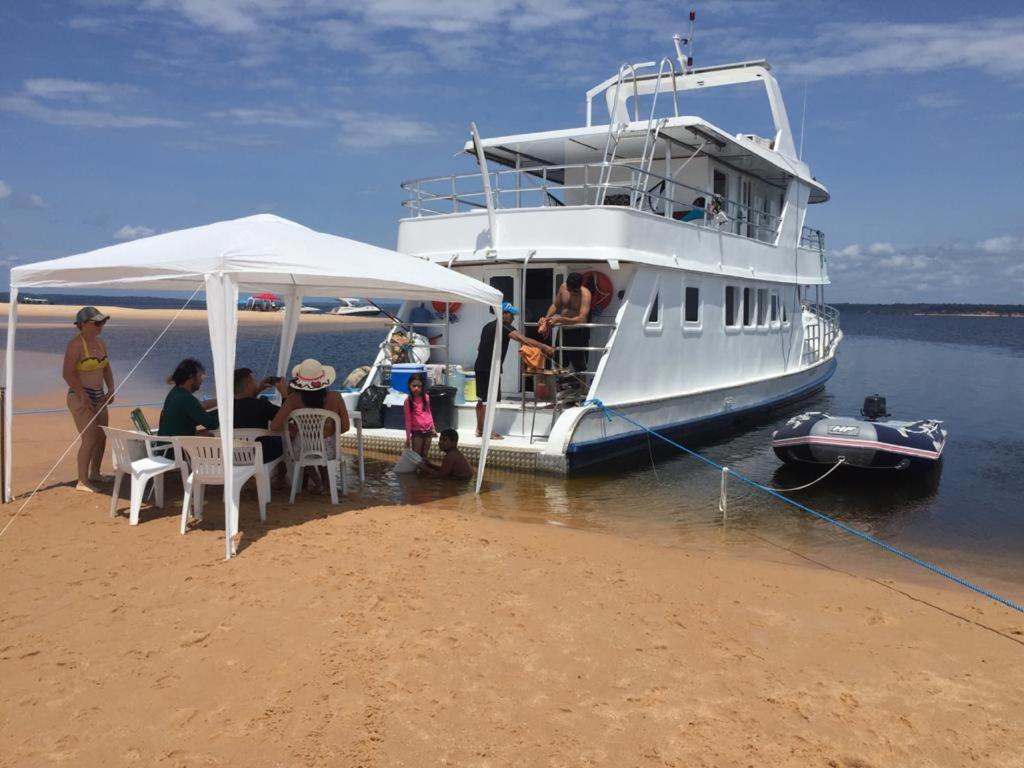 a group of people sitting on a boat on the beach at Barco Seu Meschede in Santarém