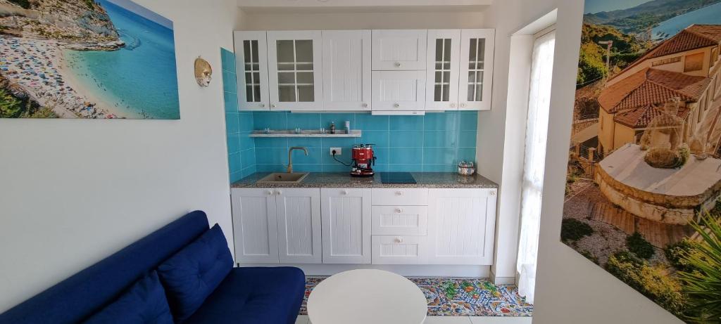 une cuisine avec des placards blancs et un mur bleu dans l'établissement MAGIK hill, à Pizzo