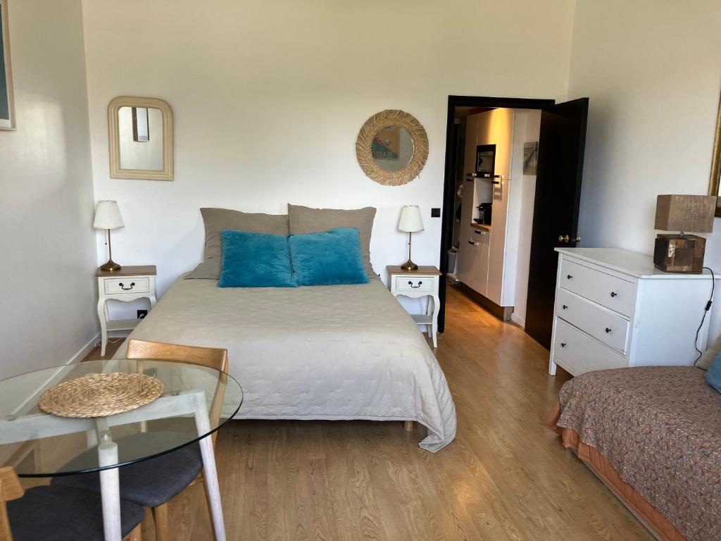 Un dormitorio con una cama con almohadas azules y una mesa. en Studio phare de Biarritz Résidence Régina Golf, en Biarritz