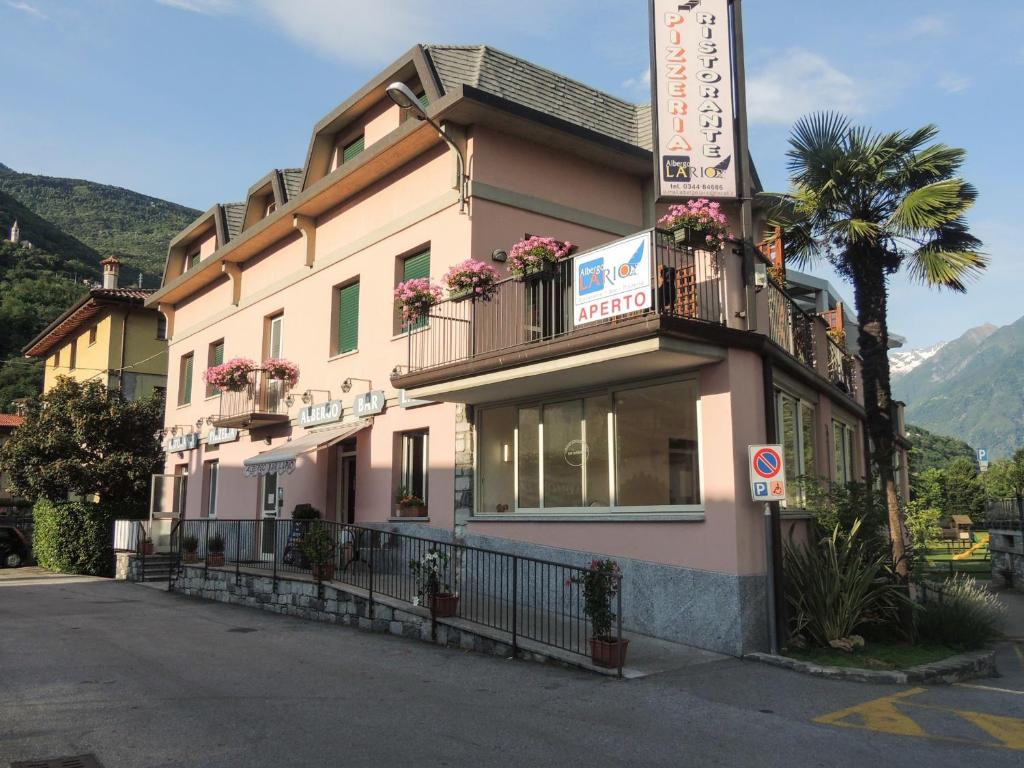 a pink building with flowers on the balconies on a street at Albergo Lario in Gera Lario