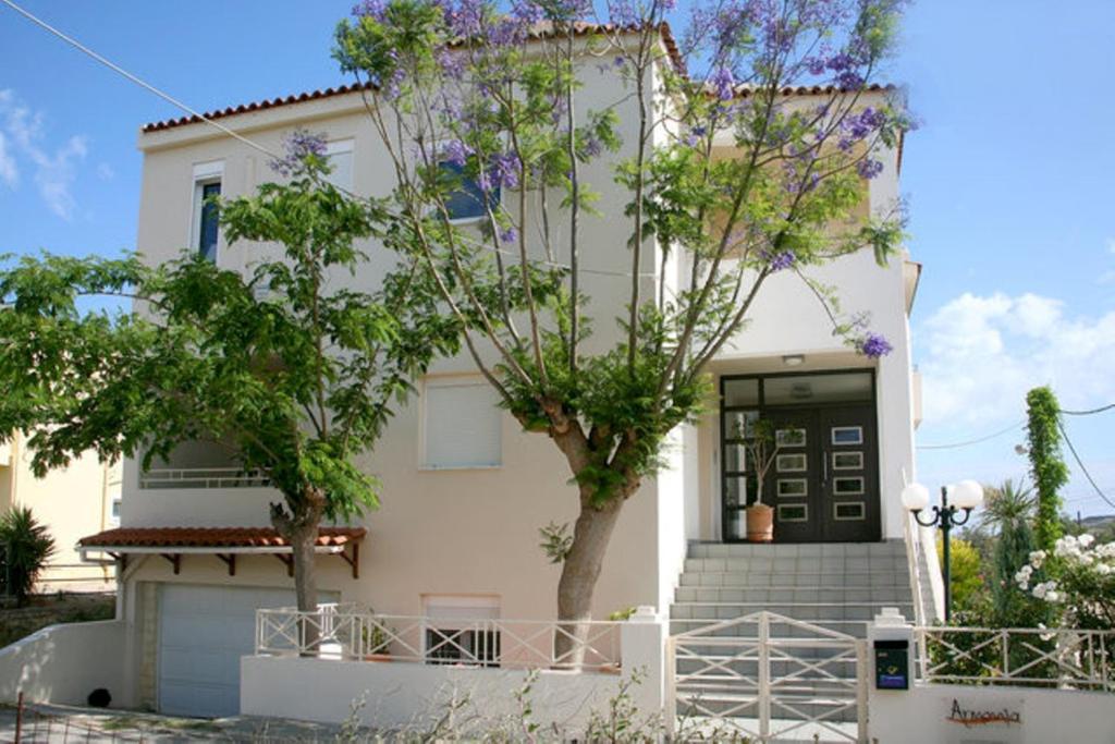 Una casa blanca con un árbol delante. en Armonia Apartments, en Almyrida