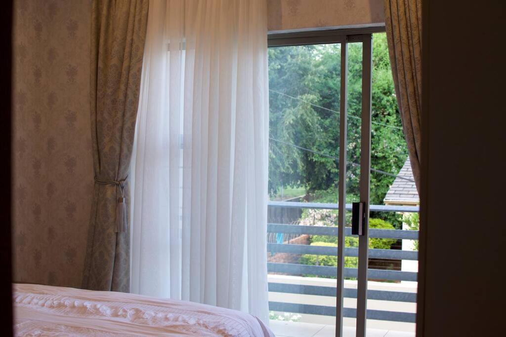 a bedroom with a window looking out at a balcony at Park Central Apartment in Pretoria