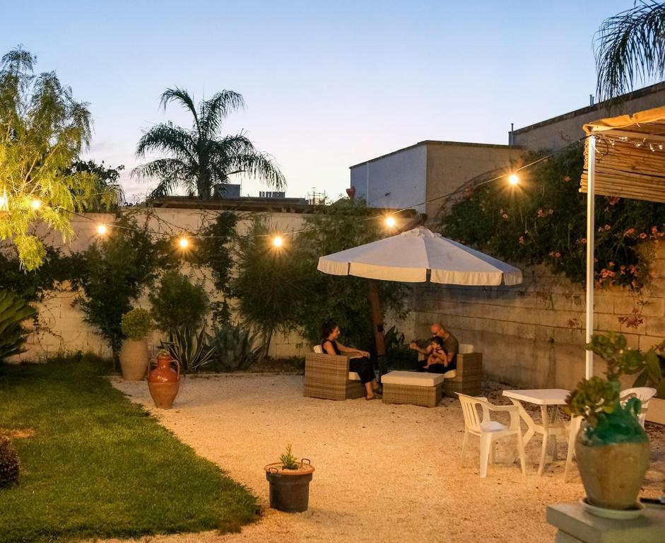 zwei Menschen, die nachts unter einem Regenschirm im Garten sitzen in der Unterkunft Terra D'Otranto in Uggiano la Chiesa