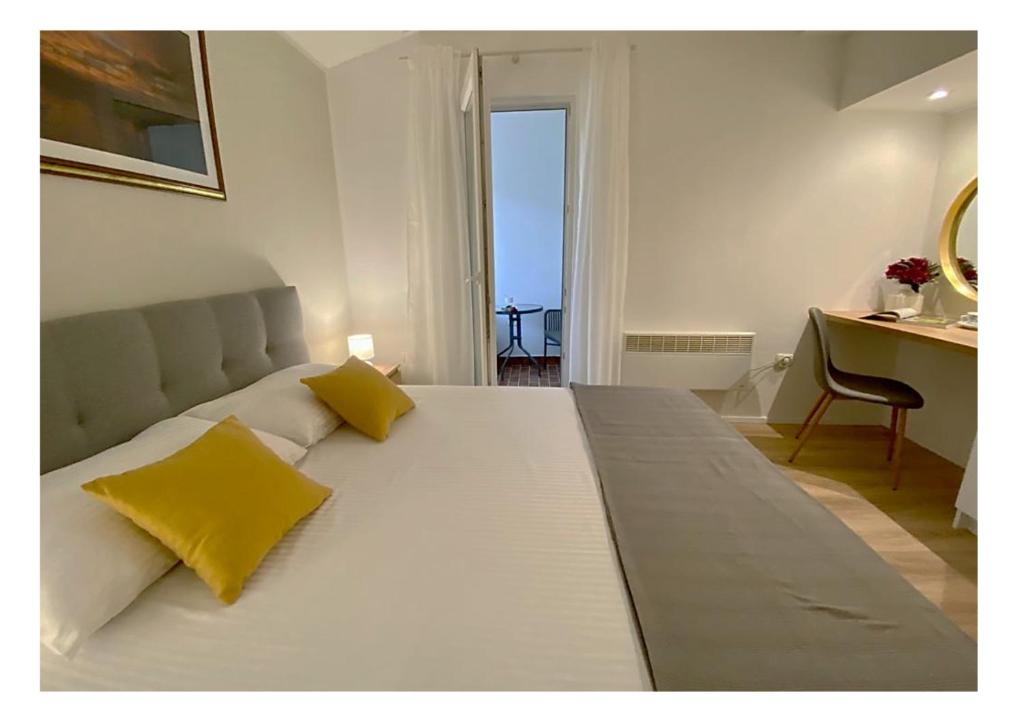 1 cama blanca grande con 2 almohadas amarillas. en Apartments Fantasia, en Pula