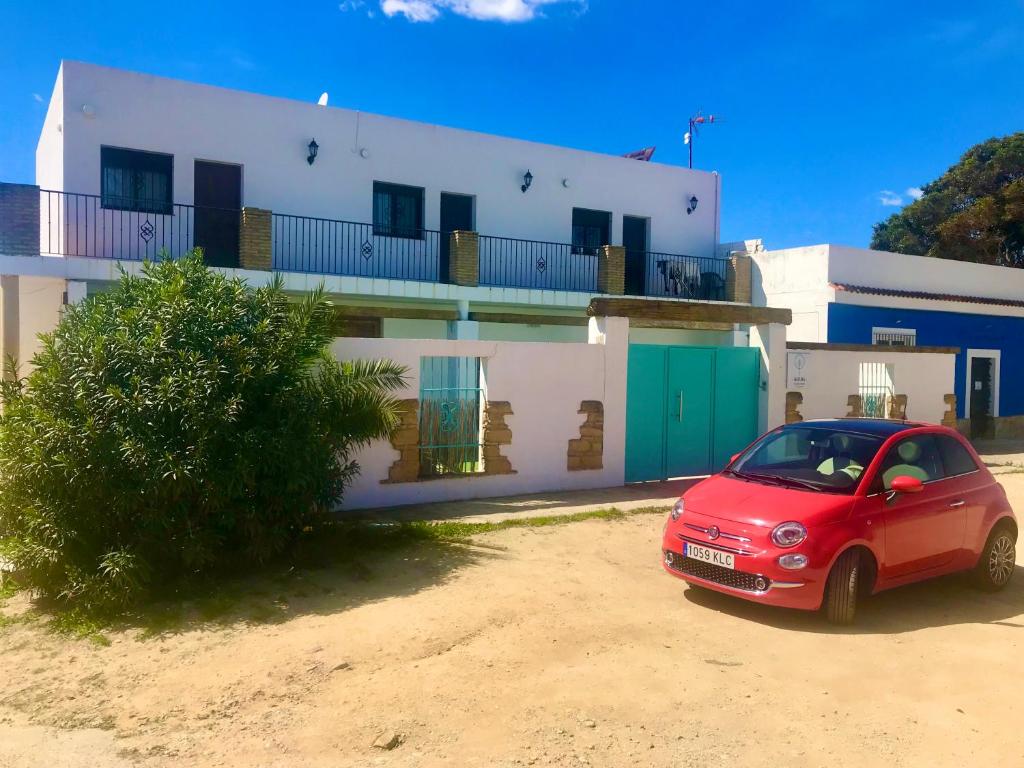 une voiture rouge garée devant une maison dans l'établissement Conil Colorado 1 rústico y económico, à Conil de la Frontera