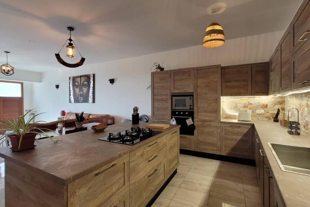 a large kitchen with wooden cabinets and a counter top at Luxury en-suite Double. Beach-house with Sea Views in Mellieħa