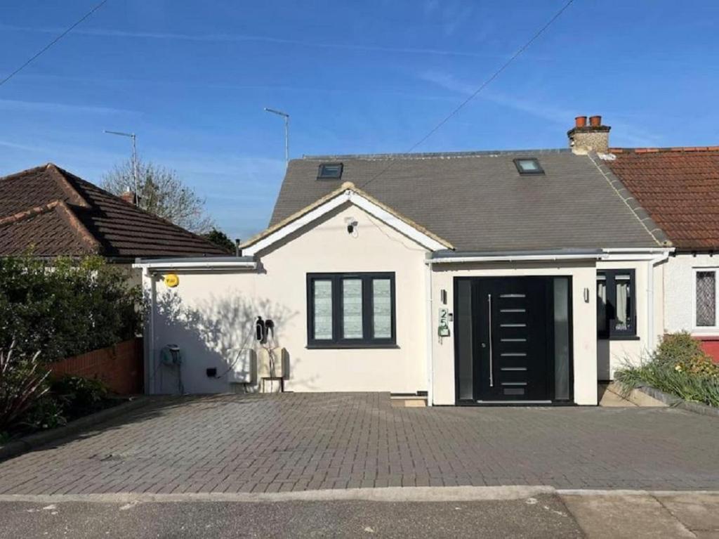 uma casa branca com uma garagem preta em Modern Family Home in Greater London em Pinner