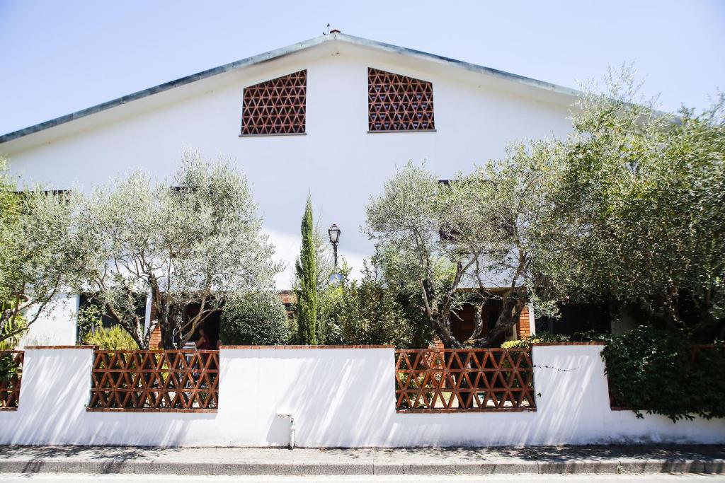 ein weißes Haus mit einem Zaun und Bäumen in der Unterkunft Enzo’s House in Lucca