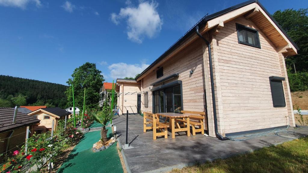 ein kleines Haus mit einer Terrasse mit einem Tisch in der Unterkunft Holzhaus am See mit Panoramablick in Trausnitz