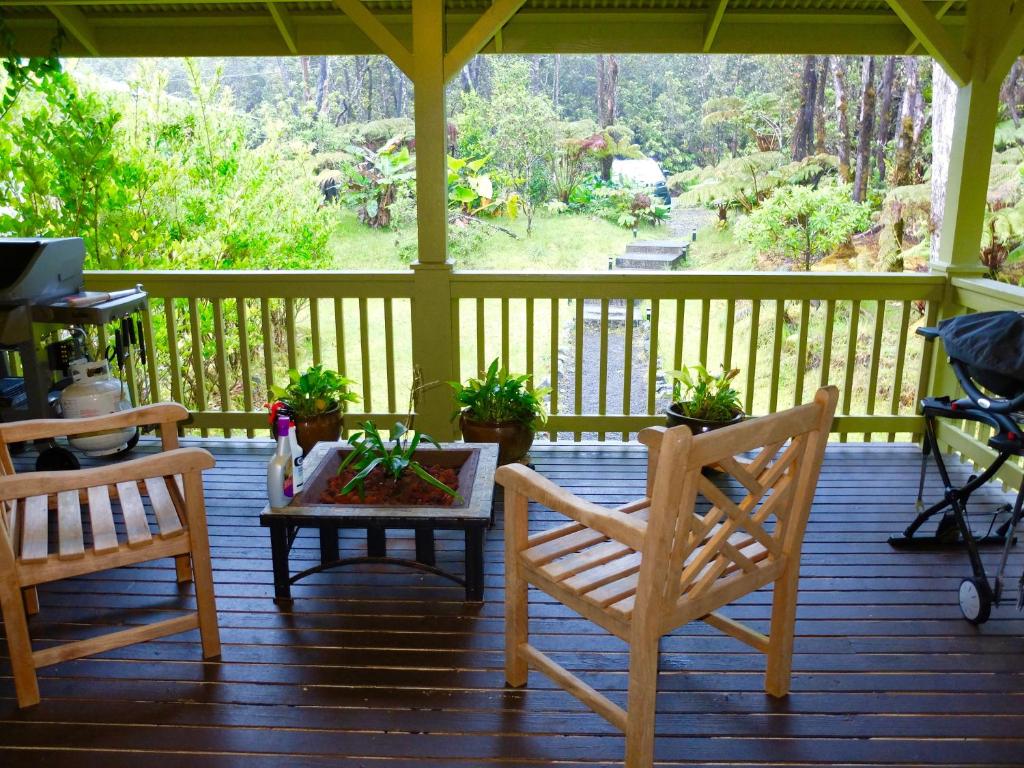 a porch with two chairs and a table with plants at Volcano One - Modern Studio with Lanai near Volcano National Park in Volcano