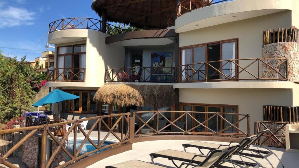 Casa con balcón con sillas y piscina en Litibu Suites Beach House, en Higuera Blanca
