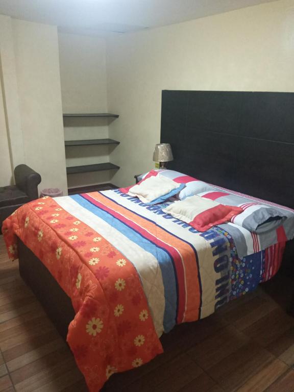a bed with a colorful blanket on top of it at Hostal la Española in Ibarra