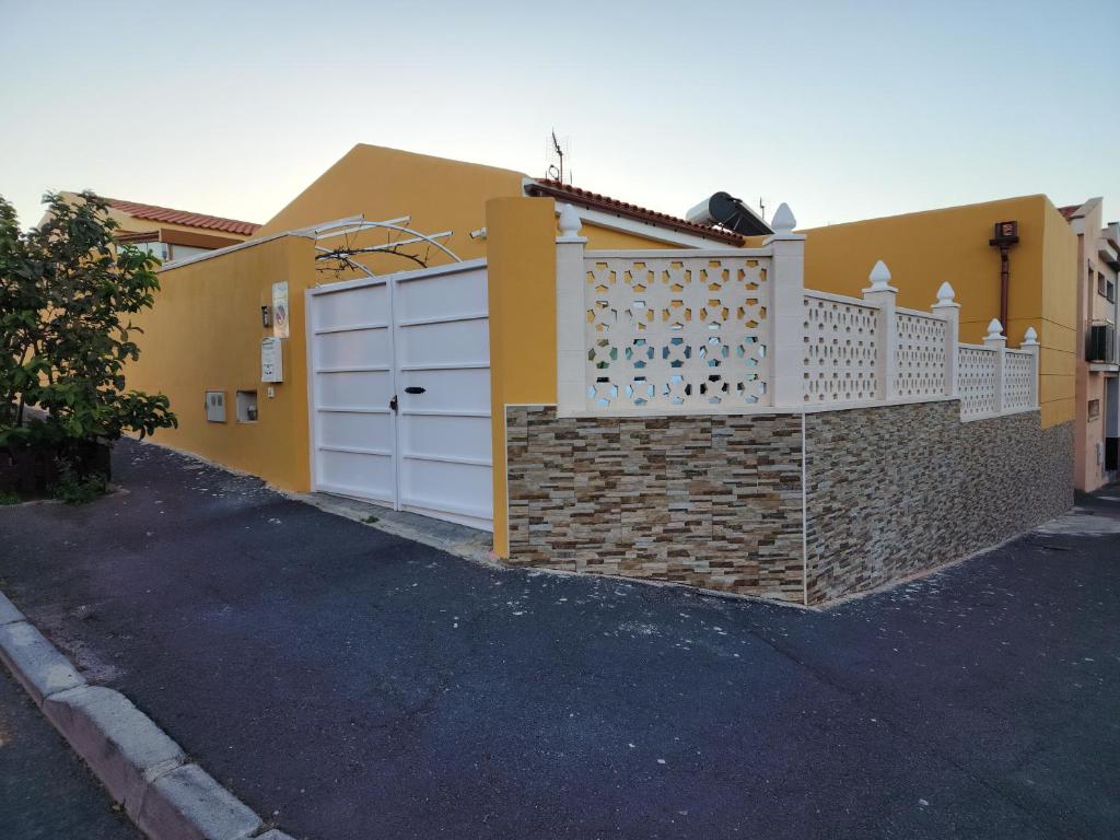 a yellow house with a fence and a garage at Casa Marta. in Granadilla de Abona