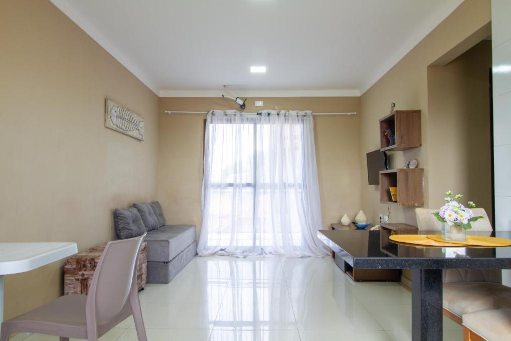 ein Wohnzimmer mit Fenster mit einer Couch und einem Tisch in der Unterkunft Flat n6 Porto de Galinhas c Piscina in Porto De Galinhas