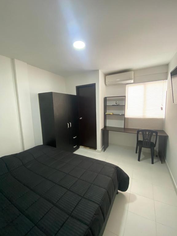a bedroom with a black bed and a desk at Cómodo apto 202 muy cerca a CC Unicentro Cúcuta in Cúcuta