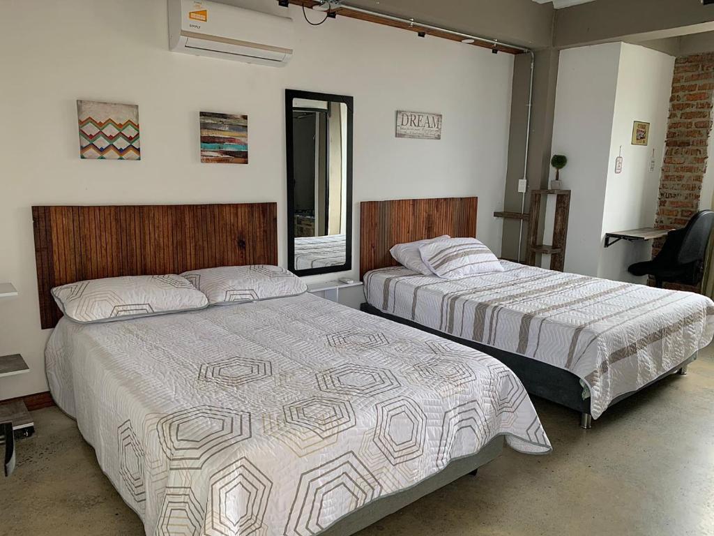 1 dormitorio con 2 camas y ventana en La Curva Apartamentos, en Cali