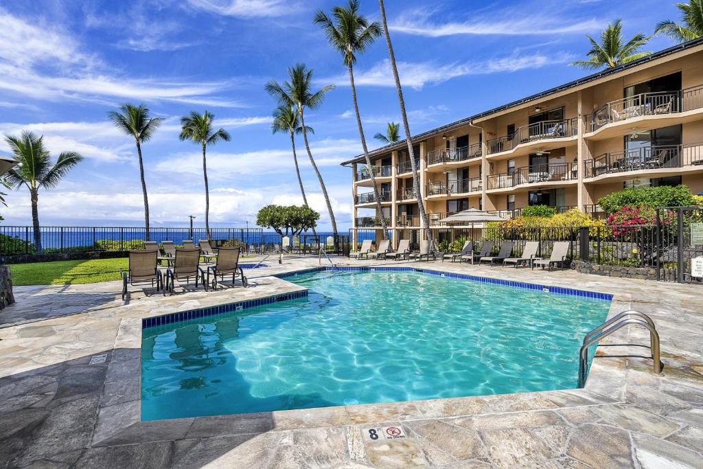 einen Pool vor einem Hotel mit Palmen in der Unterkunft Kona Makai 2103 in Kailua-Kona