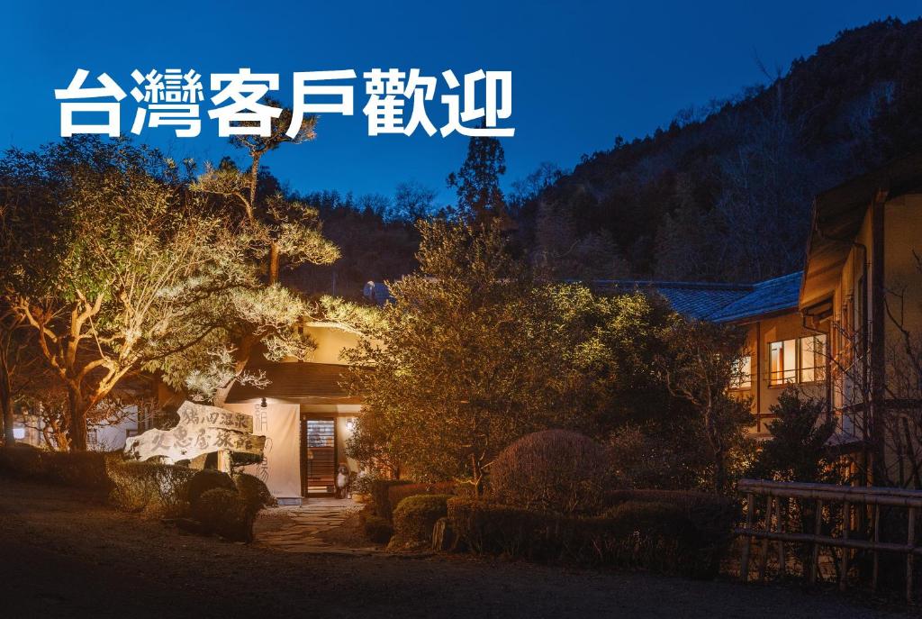 una vista nocturna de una casa con un cartel que dice en Hisaeya Ryokan, en Fujioka