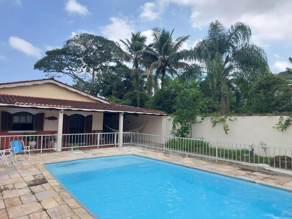 uma piscina em frente a uma casa com palmeiras em Casa Guarujá c/ piscina grande no Guarujá