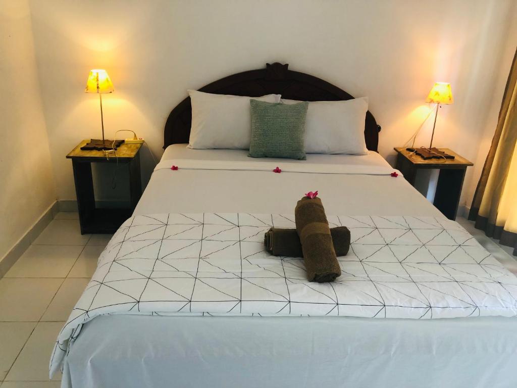 a bedroom with a large white bed with two lamps at Rumah DOLE in Gili Islands